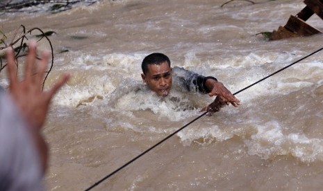 Seorang regu penyelamat menyeberangi sungai saat mencari korban tanah longsor akibat gempa di Serempah, provinsi Aceh, Indonesia, Jumat (5/7).  (AP/Binsar Bakkara)