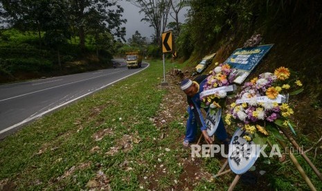 Seorang relawan membenahi karangan bunga duka cita di tempat kejadian perkara terbaliknya bus di Tanjakan Emen, Kabupaten Subang, Jawa Barat, Selasa (27/2). 