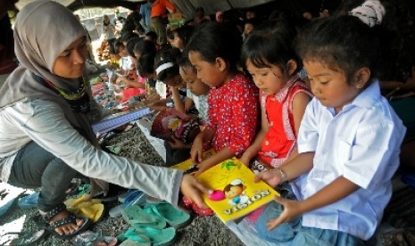 Seorang relawan menghibur anak-anak pengungsi korban dampak erupsi Gunung Kelud, di Dusun Laharpang, Kediri, Jawa Timur.