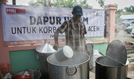 Seorang relawan tengah memasak di dapur umum.