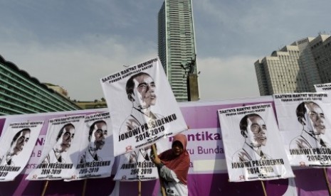 Seorang simpatisan pasangan Capres dan Cawapres Joko Widodo dan Jusuf Kalla membawa poster Jokowi ketika berlangsungnya Car Free Day di Jakarta, Minggu (1/6). Aksi tersebut untuk memberikan dukungan kepada pasangan Jokowi dan Jusuf Kalla dalam pilpres 2014