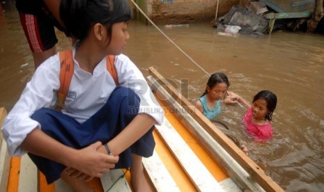  Seorang siswa berangkat sekolah menggunakan sampan untuk melintasi banjir yang merendam rumah mereka di Kampung Pulo, Jakarta Timur, Jumat (6/12).    (Republika/Rakhmawaty La'lang)