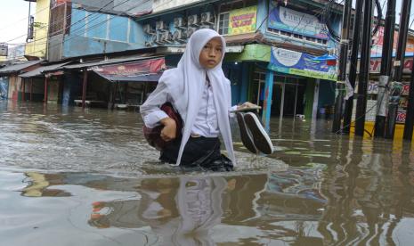 Seorang siswa berjalan menerobos banjir di Taman Narogong Indah, Bekasi, Jawa Barat, Jumat (7/10/2022). Hujan lebat yang turun sepanjang Jumat (7/10/2022) siang hari mengakibatkan banjir di sejumlah kawasan di Bekasi. 