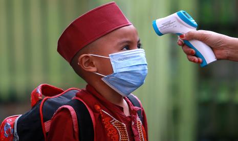 Seorang siswa diukur suhu tubuh sebelum masuk kelas di SDN 1 Kabila, Kabupaten Bone Bolango, Gorontalo, Jumat (10/9). Pemerintah Kabupaten Bone Bolango kembali membuka Pembelajaran Tatap Muka (PTM) terbatas dengan sistem belajar secara bergantian dan 50 persen siswa berada dalam kelas.