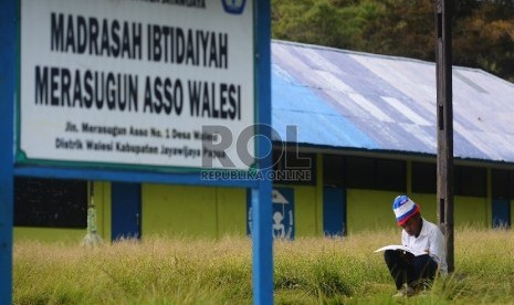 Seorang Siswa membaca buku di halaman sekolah setelah melakukan kegiatan belajar mengajar di Madrasah Ibtidaiyah Yapis Walesi, Wamena, Kabupaten Jayawijaya, Papua, Senin (27/7).