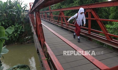 Seorang siswa SD berlari di jembatan saat akan ke sekolah untuk mengikuti Ujian Nasional (UN) di Desa Klambir V, Deli Serdang, Sumatera Utara, Senin (15/5). Ujian Nasional tingkat SD dilaksanakan secara serentak pada 15 - 17 Mei 2017.