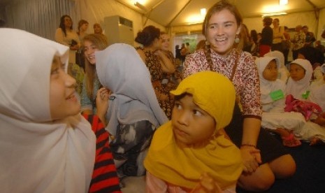 Seorang siswi pertukaran asal Amerika berbincang dengan sejumlah anak dari Komunitas Ciliwung Depok pada acara berbuka puasa bersama di kediaman Wakil Kedutabesar Amerika Serikat untuk Indonesia, Kristen Bauer di kawasan Menteng, Jakarta, Senin (7/7).