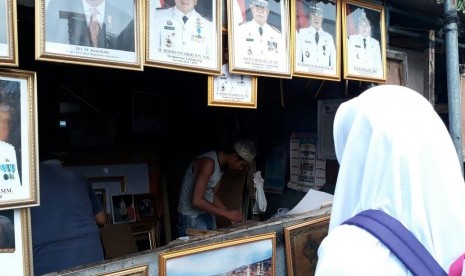 Seorang siswi sedang melihat-lihat figura bergambar pahlawan