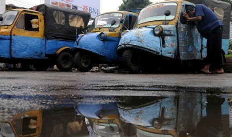 Seorang supir bemo memperbaiki bemo miliknya yang rusak di kawasan Bendungan Hilir, Jakarta Pusat, Sabtu (31/3). Di tengah persaingan yang cukup ketat dengan bertumbuhnya kendaraan umum modern di Ibukota, para supir bemo mengaku harus mencari akal agar dap