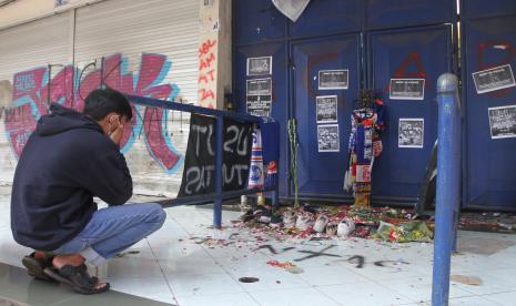 Seorang suporter Arema FC (Aremania) berdoa di depan pintu tribun 12 Stadion Kanjuruhan, Malang, Jawa Timur, Selasa (4/10/2022). Menurut sejumlah saksi mata korban terbanyak dalam tragedi Kanjuruhan berada di pintu tribun 11, 12, dan 13 yang saat kejadian pintu keluar tersebut terkunci sehingga penonton yang menghindari gas air mata tidak dapat keluar.