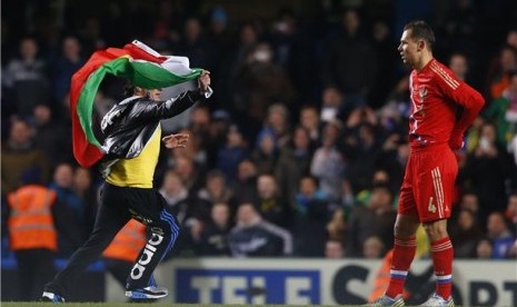 Seorang suporter (kiri) berlari masuk lapangan sambil membawa bendera saat Brasil menghadapi Rusia di laga persahabatan di Stadion Stamford Bridge, London, Senin (25/3). 