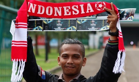 Seorang suporter sepak bola menunjukkan tiket semi final Piala AFF 2016 di kawasan Gelora Bung Karno (GBK), Jakarta, Jumat (2/12). Sebanyak 10 ribu tiket semi final Piala AFF 2016 khusus kategori dua dijual secara manual dikarenakan banyaknya kendala pemes