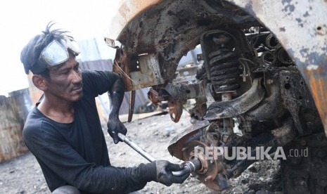 Seorang teknisi berusaha melepas onderdil yang masih bisa digunakan dari mobil yang hangus terbakar pasca unjuk rasa yang berujung anarkis di Jalan Trans Papua Pikhe, Wamena, Kabupaten Jayawijaya, Papua, Rabu (9/10/2019). 