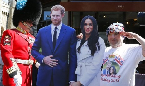 Seorang tentara melihat turis yang berfoto dengan patung karton Pangeran Harry dan Meghan Markle di Windsor, Inggris, (15/5).