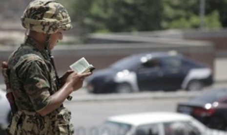 Seorang tentara Mesir membaca Al Quran, ketika bertugas menjaga masjid Al Azhar di Kairo, Mesir. (AP)