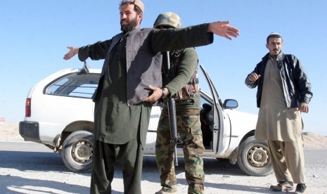 Seorang Tentara Nasional Afghanistan memeriksa seorang warga di sebuah pos pemeriksaan di provinsi Helmand, Afghanistan, Rabu 23/12. 