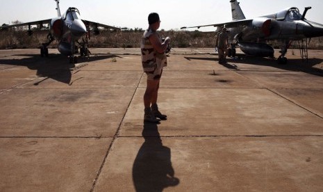  Seorang tentara Perancis berdiri di antara dua jet tempur Mirage F1 di pangkalan udara militer Mali di Bamako, Senin (14/1). (Reuters/Joe Penney)