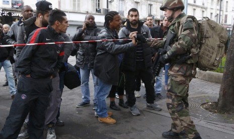 Seorang tentara Prancis memeriksa surat-surat identitas seorang pria di kawasan Saint-Denis, Prancis, dekat Paris, November 18, 2015(  Reuters/Jacky Naegelen)