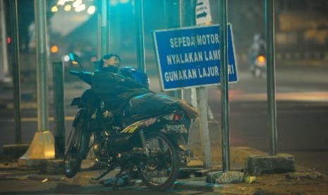 Seorang tukang ojek terlelap di atas sepeda motornya di lampu lalulintas Jl Gatot Subroto - Kuningan, Jakarta