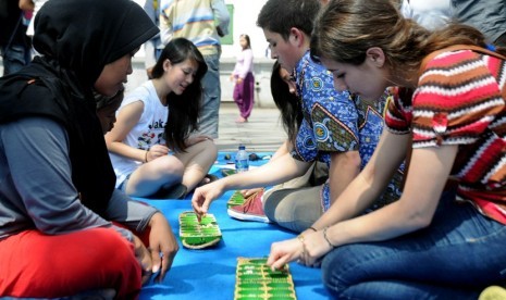  Seorang turis asing mencoba permainan tradisional congklak pada acara Jakarta Festival Museum Day 2012, di Taman Fatahillah, Jakarta Barat, Sabtu (19/5).  (Prayogi/Republika)