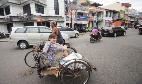 Seorang turis Belanda menaiki becak berkeliling kota tua Padang, Sumatra Barat, Senin (1/12).