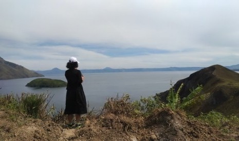 Seorang turis lokal memandangi keindahan Danau Toba dari atas bukit.