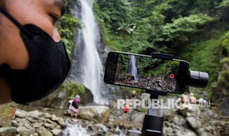 Seorang vlogger merekam video suasana dan aktivitas pengunjung wisata alam Curug Cigeuntis di Desa Mekarbuana, Tegalwaru, Karawang, Jawa Barat. Ada trik khusus yang bisa digunakan agar video perjalanan yang kita buat lebih menarik banyak viewers.