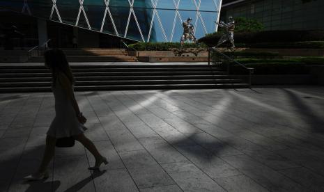 Seorang wanita berjalan di luar Hong Kong Exchange Square, Kamis, 28 Juli 2022. Pengadilan Tinggi Hong Kong membatalkan pembatasan pelaporan pengadilan untuk kasus keamanan nasional pada Selasa (2/8/2022). 