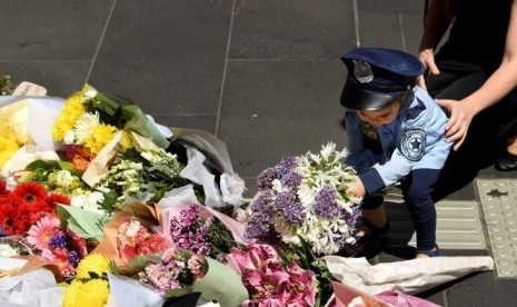 Seorang wanita dan anak-anak meletakan bunga di monumen di Bourke Street bagi para korban amukan sebuah kendaraan.