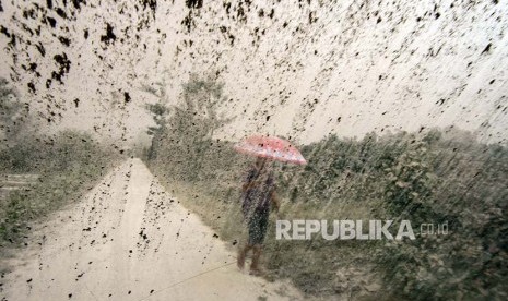 Seorang wanita menggunakan payung berlindung dari hujan (ilustrasi)