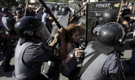 Seorang wanita didorong polisi antihuru-hara dalam bentrokan dengan demonstran yang memprotes Piala Dunia 2014 di Sao Paulo, Brasil, Kamis (12/6). 