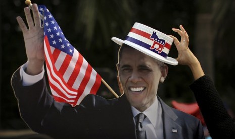 Seorang wanita India menempatkan topi pada potongan karton poster Presiden Barack Obama dalam acara yang diselenggarakan oleh Kedubes AS di New Delhi, Rabu (7/11).       (AP/Kevin Frayer)