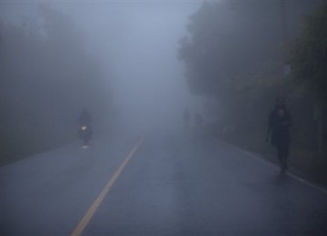 Seorang wanita (kanan) berjalan di bawah guyuran hujan lebat di sebuah jalan di Santa Rosa, Guatemala, Kamis (13/10).