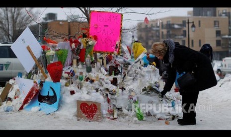 Pengajuan Bebas Bersyarat Pembunuh Masjid Quebec Dikurangi. Seorang wanita meletakkan bunga tidak jauh dari  TKP penembakan di Masjid di Pusat Kebudayaan Islam Quebec, Quebec City, Kanada pada 2017.