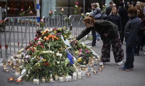 Seorang wanita meletakkan karangan bunga di depan sebuah toko di Ahlens, Sabtu (8/4). Aksi ini sebagai bentuk simpati atas peristiwa terorisme di Stockholm. 