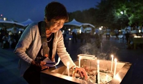 Seorang wanita meletakkan lilin di Peace Memorial Park Hiroshima, saat peringatan 71 tahun bom nuklir dijatuhkan di Kota Hiroshima