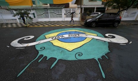 Seorang wanita melewati grafiti yang dibuat di jalan untuk menyambut Piala Dunia 2014 Brasil. 