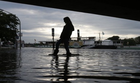  Seorang wanita memakai sepatu bot karet berjalan melintasi genangan air di bawah jembatan di Dresden, Jerman, Senin (3/6) waktu setempat.    (AP/Markus Schreiber)