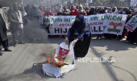 Seorang wanita membakar patung Perdana Menteri India Narendra Modi sementara dia bersama yang lain mengambil bagian dalam demonstrasi yang diselenggarakan oleh Awami Rickshaw Union untuk memprotes larangan gadis Muslim mengenakan jilbab di kelas di beberapa sekolah, di negara bagian Karnataka, India selatan, di Lahore , Pakistan, Kamis, 10 Februari 2022. Berjilbab di Kelas Dilarang, Muslim India Khawatir Masa Depan Pendidikan Muslimah