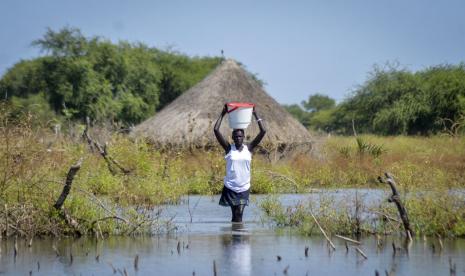 Seorang wanita membawa ember di kepalanya saat dia mengarungi banjir di desa Wang Chot, daerah Old Fangak, negara bagian Jonglei, Sudan Selatan pada 26 November 2020.