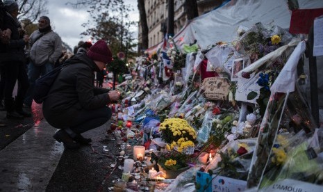 Seorang wanita memberikan penghormatan untuk korban serangan Paris di depan Bataclan konser, Rabu 25 November, 2015, di Paris.