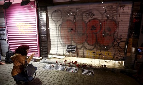 Seorang wanita mengambil gambar karangan bunga serta kartu yang diletakkan di tempat bom bunuh diri terjadi di Istanbul, Turki, pada Sabtu (19/3).