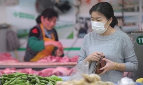 Seorang wanita mengenakan masker saat berbelanja di sebuah pasar di Shanghai.