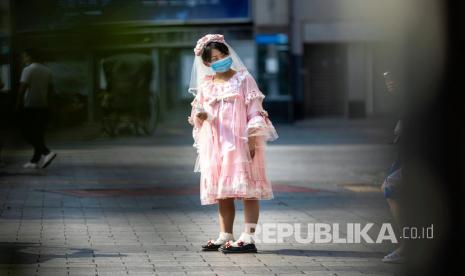 Seorang wanita mengenakan masker saat berjalan di Guangzhou, Guangdong, Cina, Selasa (28/4). Menlu China serang politisi yang menurutnya melabeli virus dan memfitnah WHO. Ilustrasi.