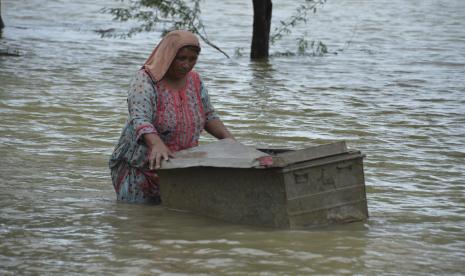  Seorang wanita menggunakan koper untuk menyelamatkan barang-barang yang dapat digunakan dari rumahnya yang dilanda banjir di Jaffarabad, sebuah distrik di provinsi Baluchistan barat daya Pakistan, Kamis, 25 Agustus 2022. 