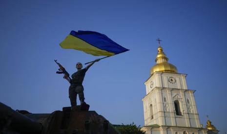 Seorang wanita mengibarkan bendera Ukraina di atas tank Rusia yang hancur di Kyiv, Ukraina, Jumat, 10 Juni 2022. Dengan perang berkecamuk di front timur dan selatan, musim panas 2022 terbukti pahit bagi ibu kota Ukraina, Kyiv. Matahari bersinar tetapi kesedihan dan tekad yang suram berkuasa.