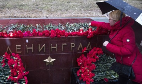 Seorang wanita menyalakan lilin mengenang korban ledakan di kereta bawah tanah St Petersburg di memorial bertuliskan Leningrad atau dikenal dengan St Peterburgs di Moskow, (3/4).