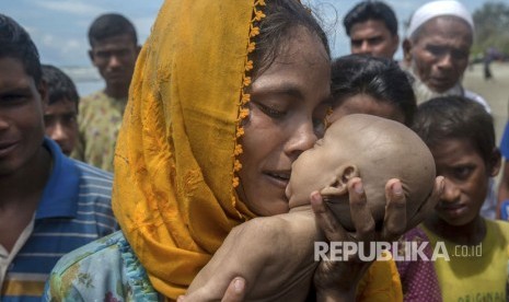 Seorang wanita Muslim Rohingya Hanida Begum, yang menyeberang dari Myanmar ke Bangladesh, mencium anak bayinya Abdul Masood yang meninggal saat kapal yang mereka tumpangi terbalik sebelum mencapai pantai Teluk Benggala, di Shah Porir Dwip, Bangladesh, Kamis  (14/9).