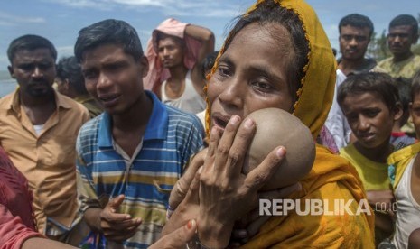 Seorang wanita Muslim Rohingya Hanida Begum, yang menyeberang dari Myanmar ke Bangladesh, sangat sedih saat memegang anak laki-lakinya, Abdul Masood yang meninggal saat kapal yang mereka tumpangi terbalik sebelum mencapai pantai Teluk Benggala, di Shah Porir Dwip, Bangladesh, Kamis (14/9).