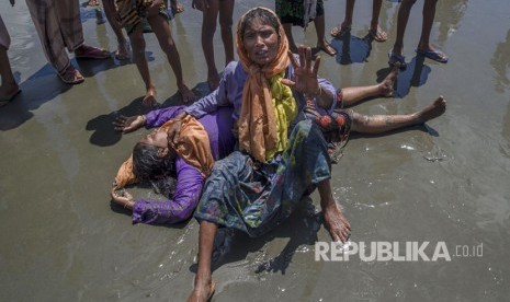 Seorang wanita Muslim Rohingya, yang menyeberang dari Myanmar ke Bangladesh, berteriak minta tolong karena kerabatnya tidak sadar setelah kapal yang mereka tumpangi dalam beberapa menit sebelum mencapai pantai di Shah Porir Dwip, Bangladesh, Kamis, (14/9).